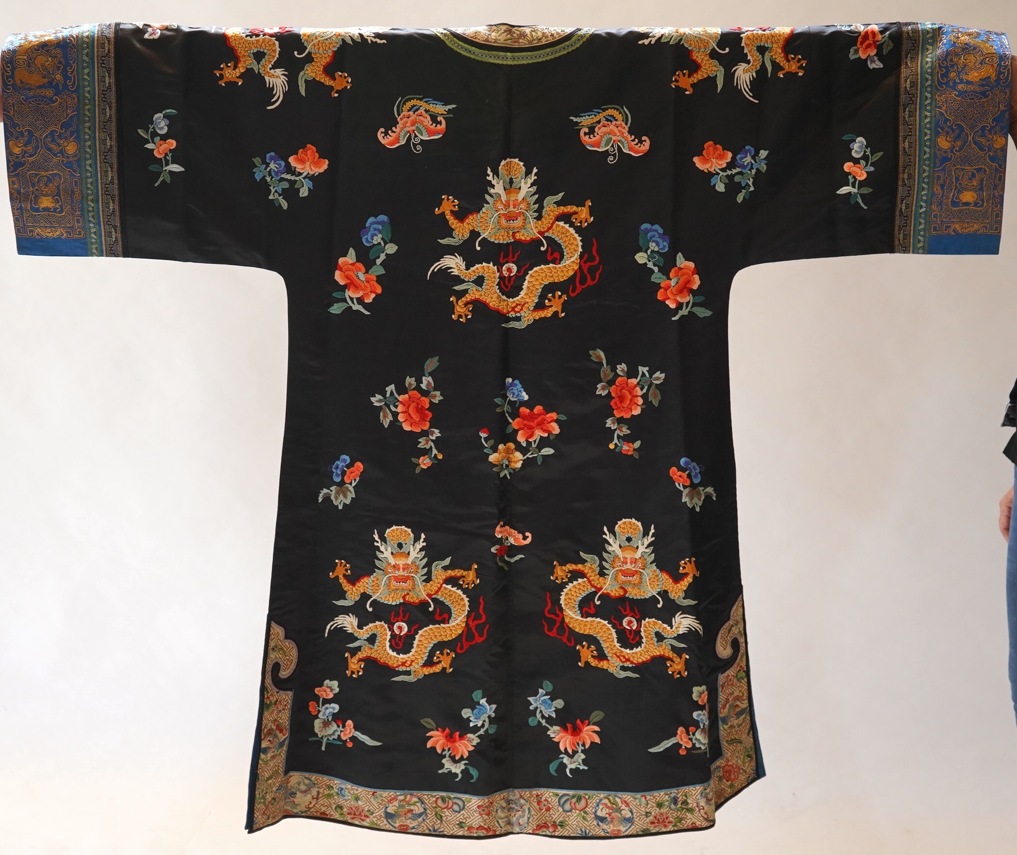 An early 20th century Chinese blue satin silk embroidered dragon robe, embroidered with five claw dragon symbols with flaming pearls, surrounded by bats and flower motifs, with gold thread embroidered dragon sleeve bands